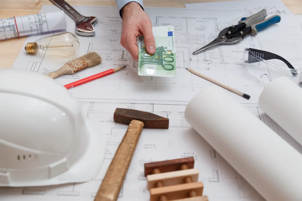 Construction blueprints, tools, hard hats, and money representing contractor project costs and budgeting